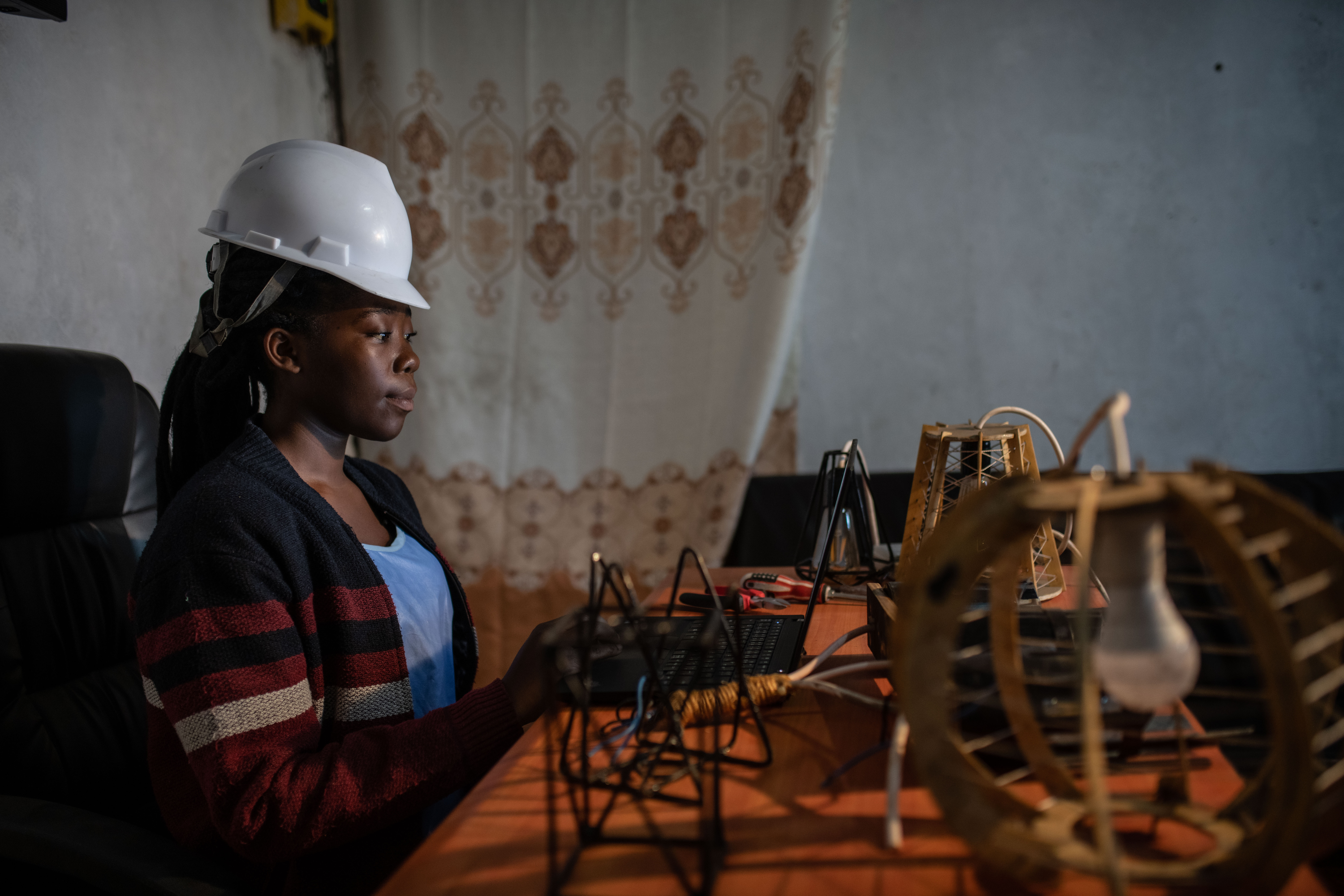 A 22 year old craftswoman works on manufacturing floor lamps