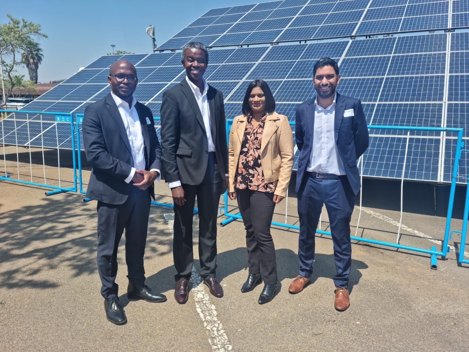 Colleagues stand near solar panels in South Africa