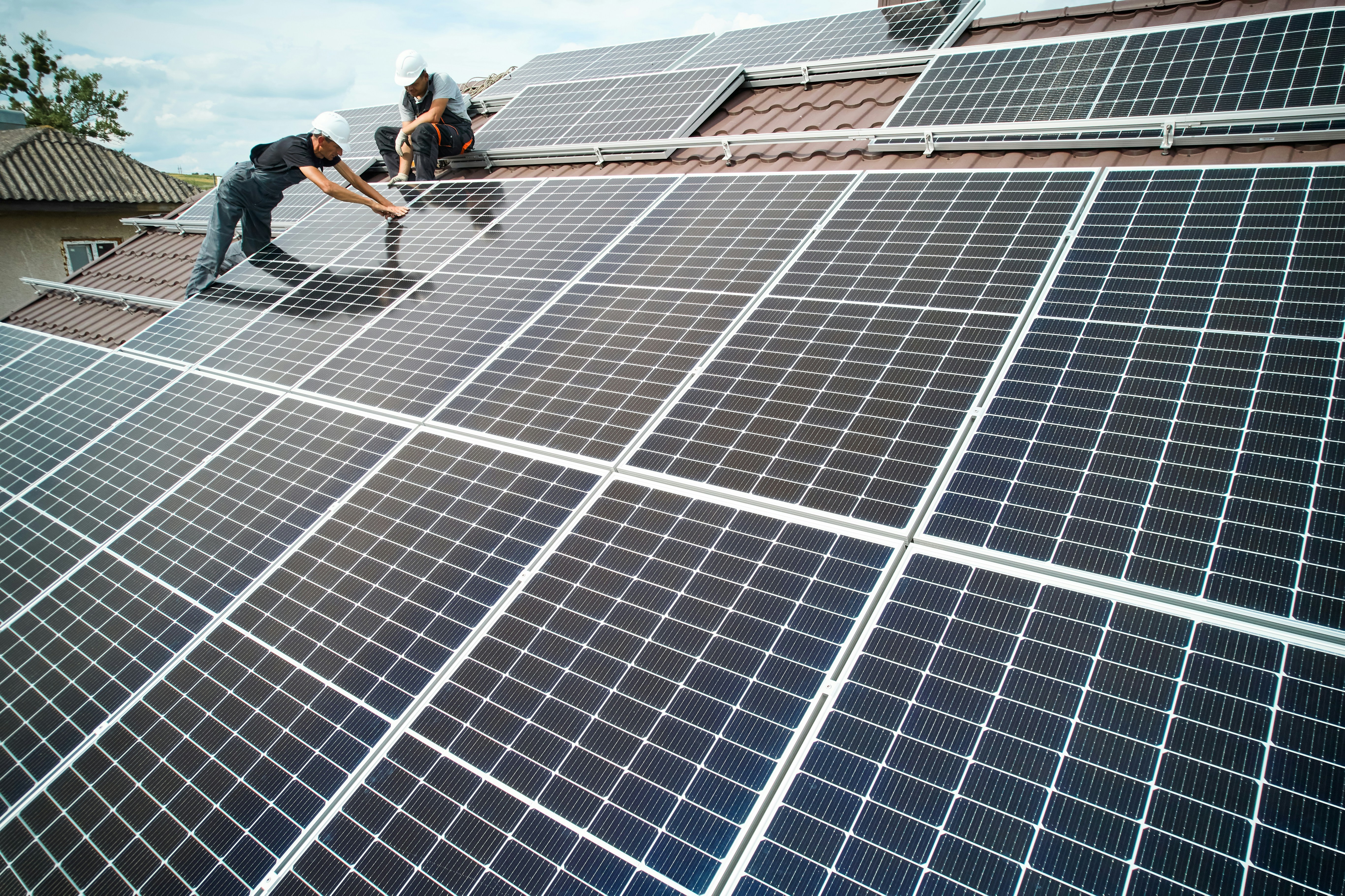 Two construction workers install a solar panel
